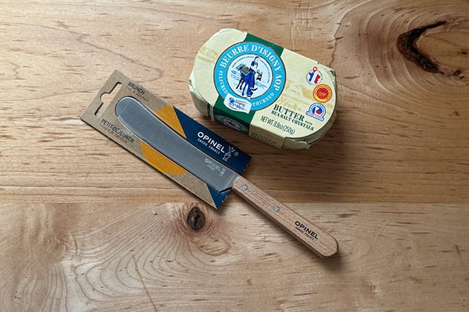 An Opinel butter spreader aside a block of fancy French butter.