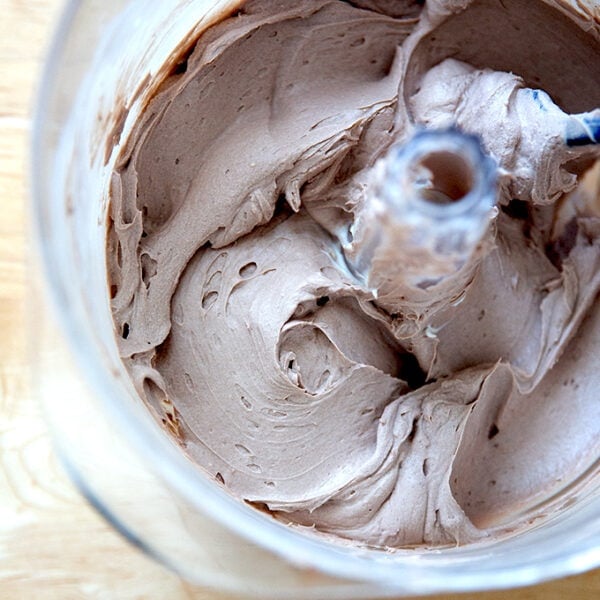 A stand mixer holding whipped chocolate cream cheese frosting.