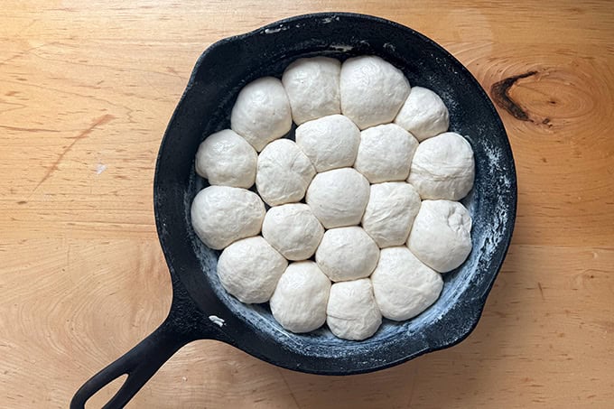 Monkey bread dough balls risen in a 9-inch cast iron skillet.