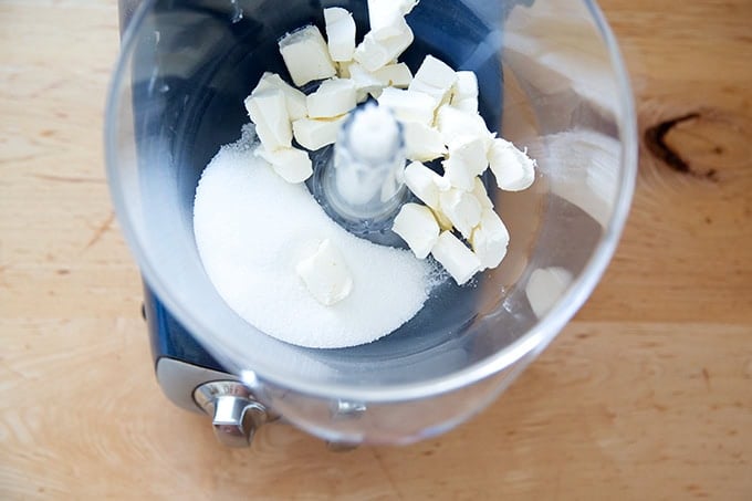 A stand mixer filled with cold cubed cream cheese and sugar.