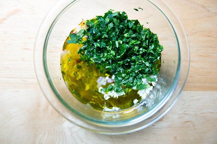 Parsley, cilantro, and olive oil added to the bowl of shallots, garlic, pepper flakes and white balsamic vinegar.