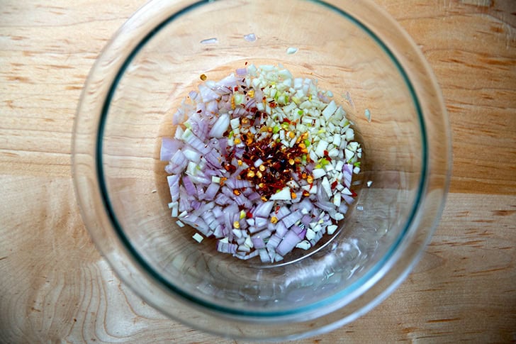 Shallots, garlic, pepper flakes and white balsamic vinegar in a bowl.